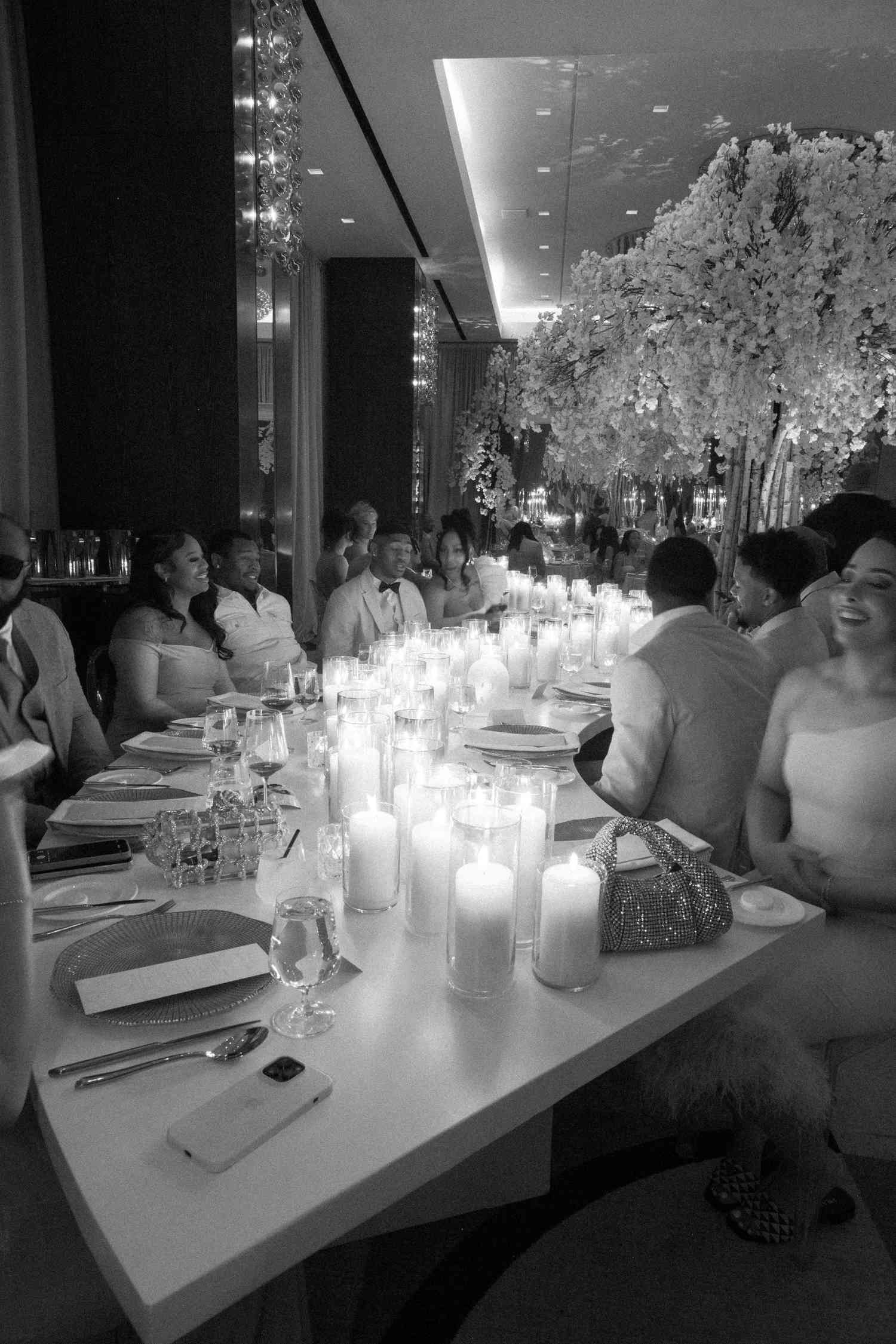 black and white photo of dinner table with candles and guests mingling