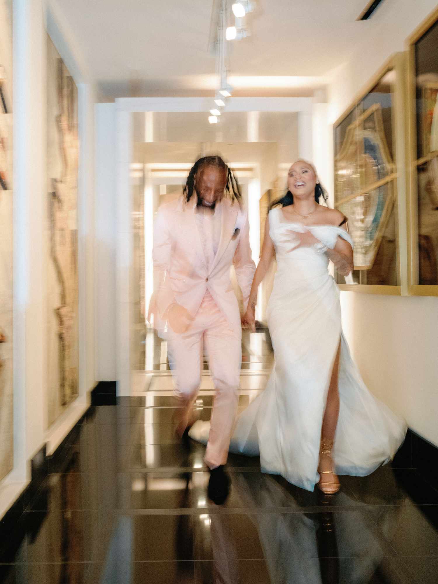 motion blur photo of bride and groom running down marble hallway