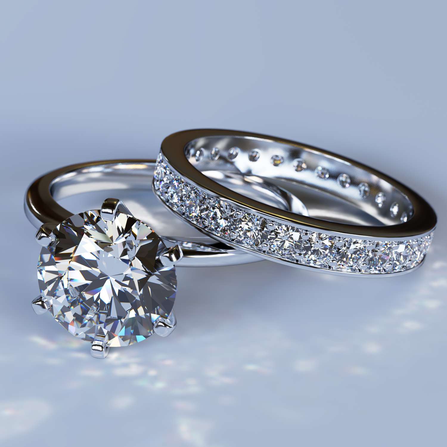 A close-up photo of a diamond engagement ring on a silver band and a diamond pavé wedding band